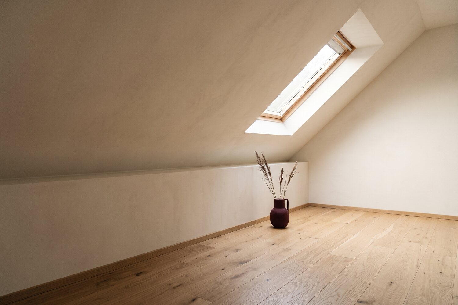 KI-generiertes Symbolbild: leeres Dachzimmer mit niedriger Wand unter der Schr&auml;ge, Dachfenster und Eichendielen